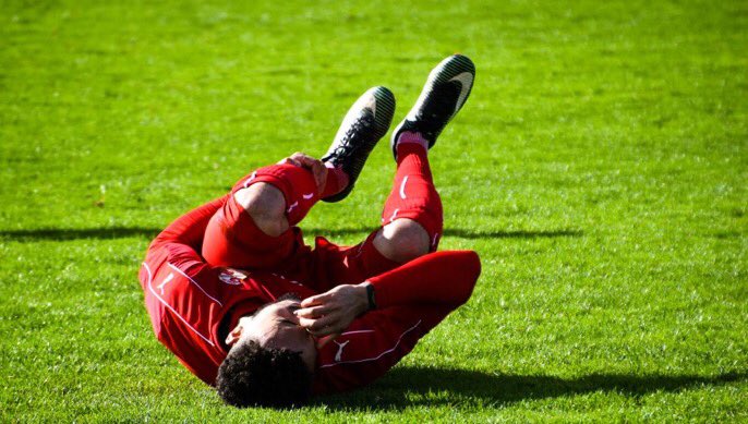 footballer lies on the pitch clutching head